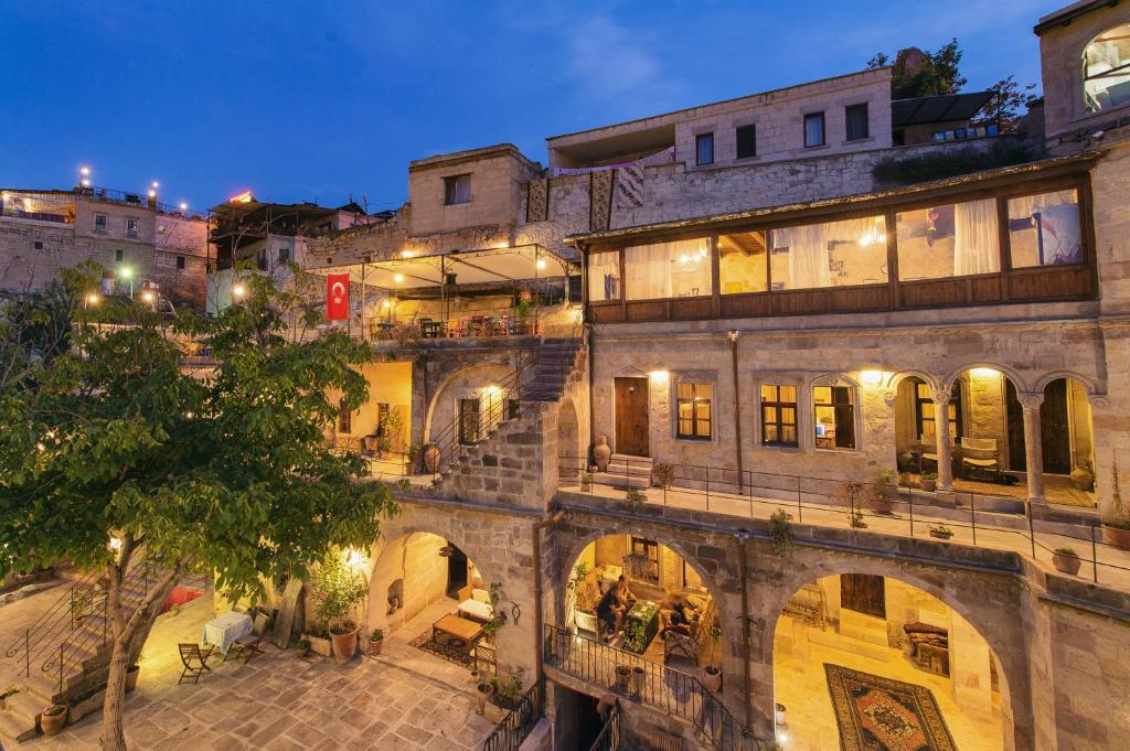 Beleuchtete Steinfassade und Innenhof des Century Cave Hotel in der Abenddämmerung